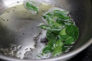 frying mustard seeds and curry leaves for making kuzhambu