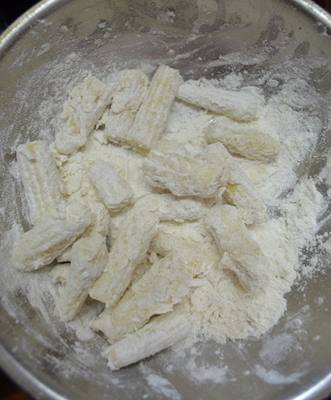 mixing baby corns in flour mixture for chilli baby corn recipe