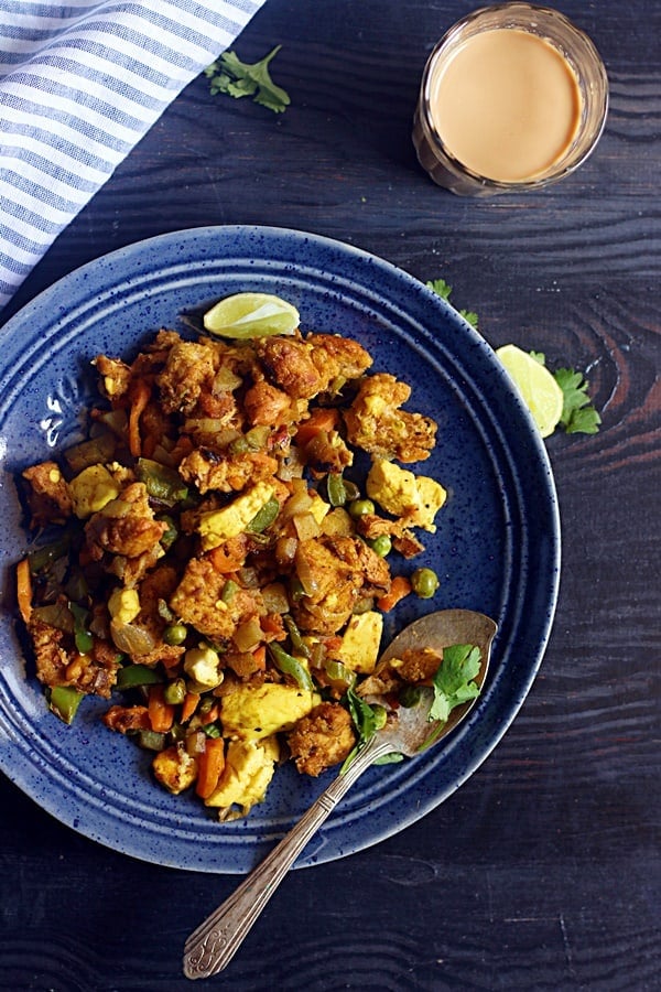 overhead shot of mixed veg bread upma served in a ceramic plate with tea for breakfast.