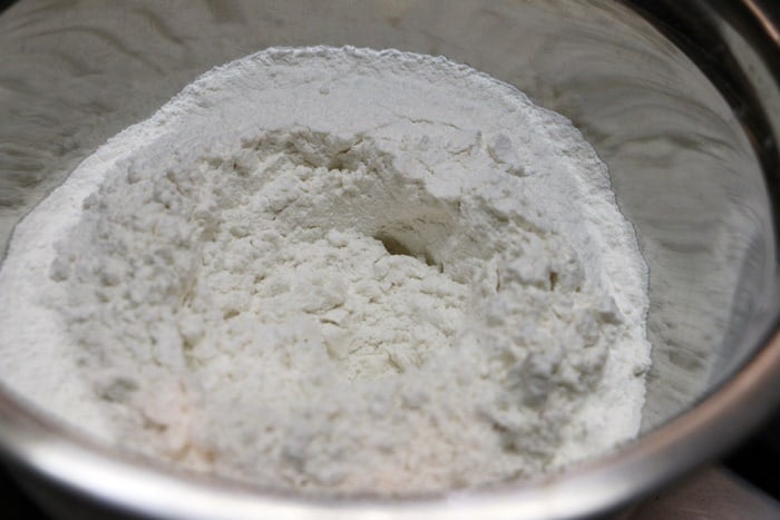 adding all purpose flour, yeast, milk, curd for making dough for butter naan