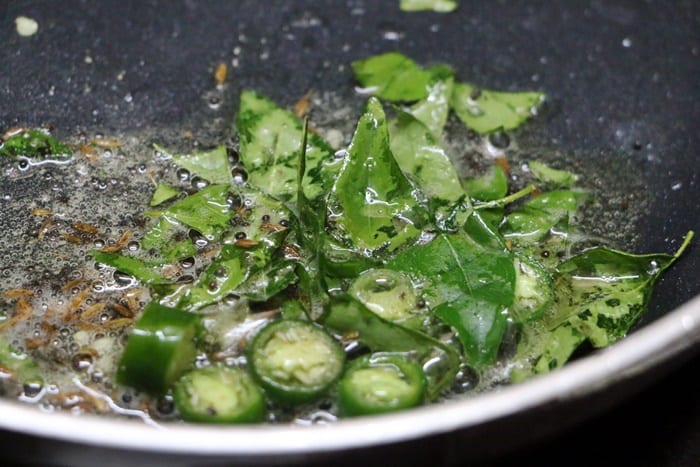 Tempering mustard seeds, chilies and curry leaves in oil