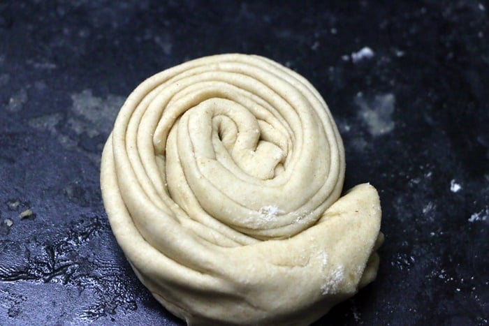shaping the pleated dough like pinwheel for making lachha paratha recipe