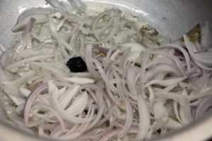 thinly sliced onions added to sautéed spices in matar pulao recipe