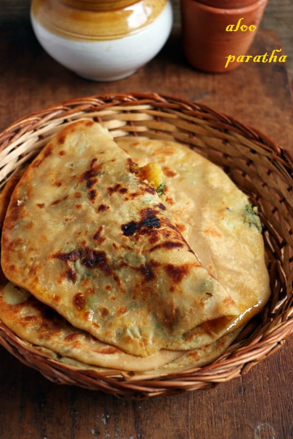 dhaba style aloo paratha served in a bamboo tray with pickle and tea