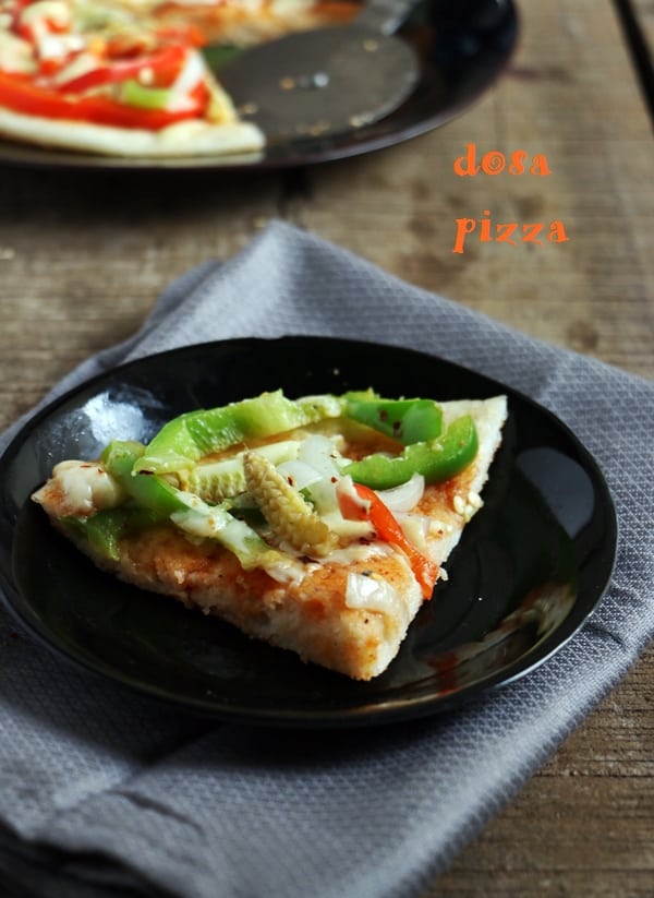 slice of pizza dosa served on a plate with more on background.