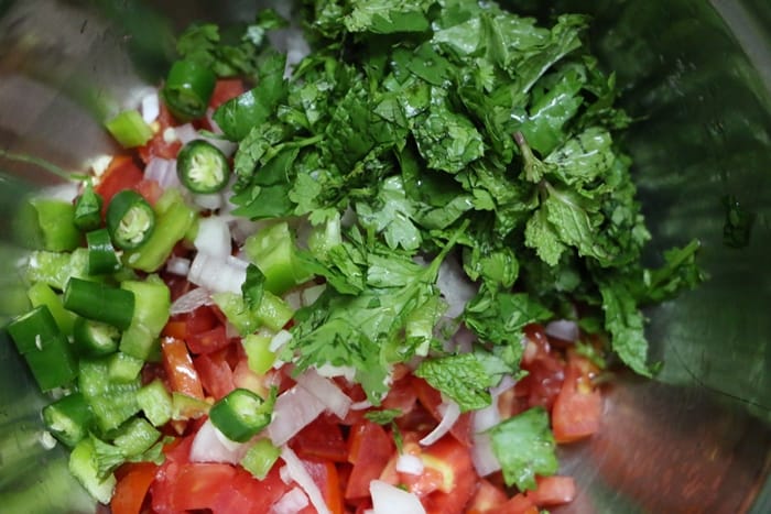 Chopped onion, tomatoes, cilantro and green chili in a mixing bowl