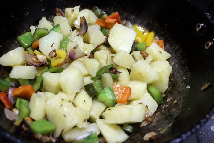 adding potatoes for making aloo capsicum recipe