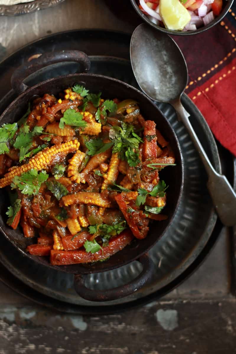 Closeup shot of vegetable jalfrezi curry served in a cast iron pan with roti for dinner