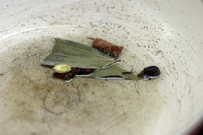 sauteing who,e spices in oil for making paneer lababdar