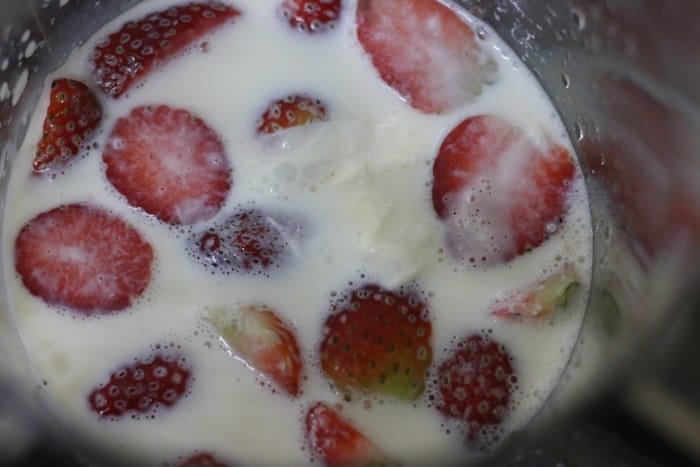 frozen strawberries and milk in a blender jar