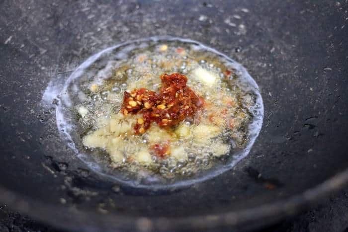 frying ginger garlic and red chilli paste in sesame oil for honey chilli potato recipe