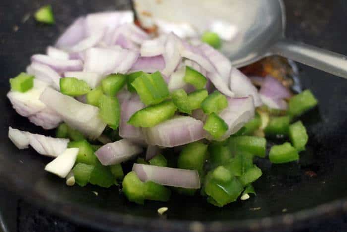 sauteing onions and green bell peppers in oil for chilli potato