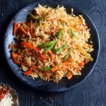 homemade schezwan fried rice in a black ceramic plate