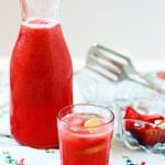 Homemade strawberry lemonade served in a glass with more lemonade in the pitcher