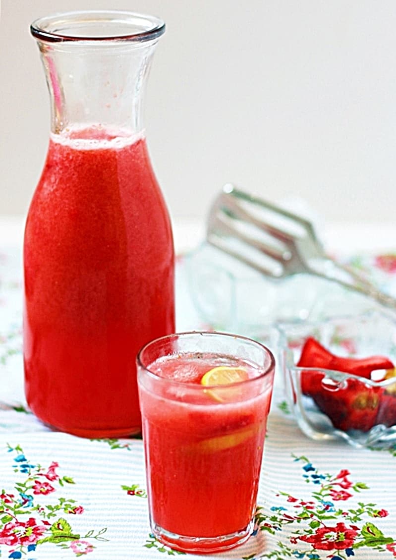 Homemade strawberry lemonade served in a glass with more lemonade in the pitcher