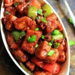 resraurant style chilli paneer served in a oval ceramic dish with a spoon