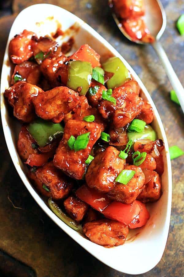 resraurant style chilli paneer served in a oval ceramic dish with a spoon