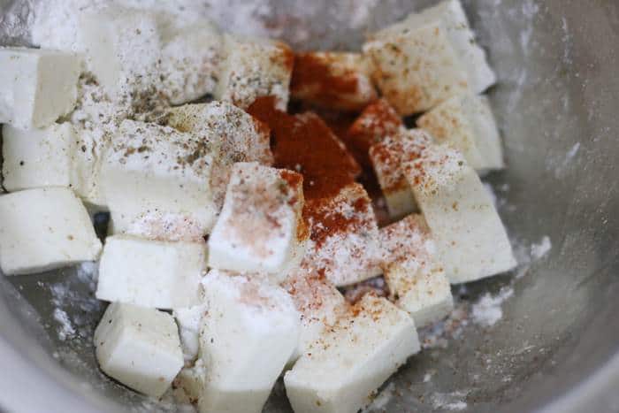 paneer cubes, red chili powder, pepper powder and salt placed in a mixing bowl.