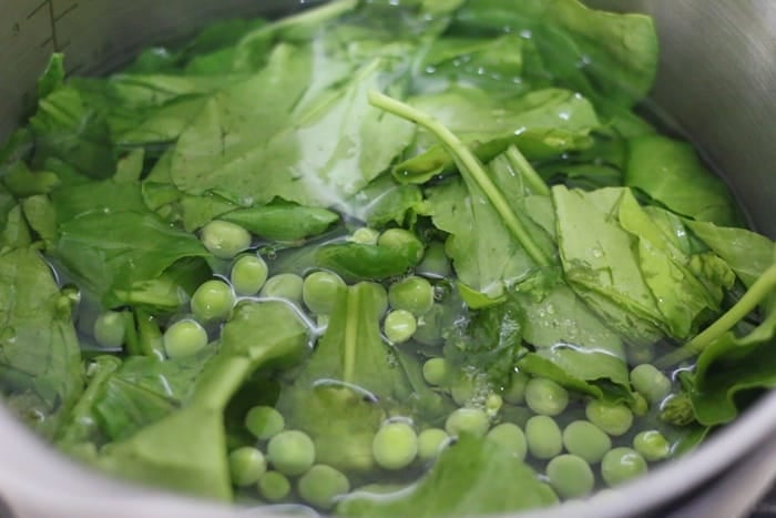 adding spinach and green peas to boiling water