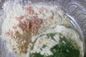 adding spice powders, gram flour and salt to mashed potatoes