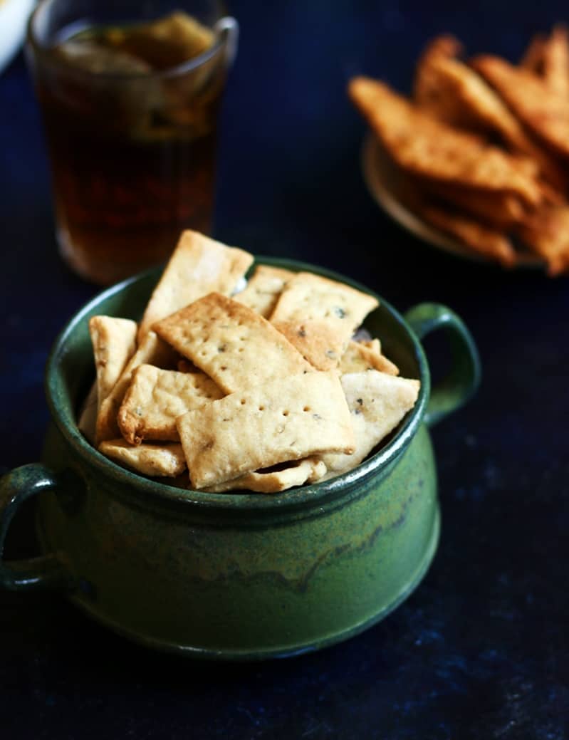 Crispy namak pare served in a green bowl with tea for snack