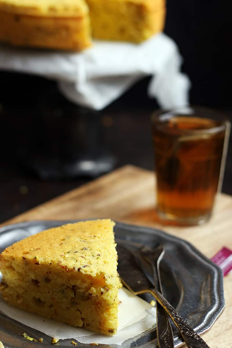 A slice of Iranian mawa cake with tea, more cake in background