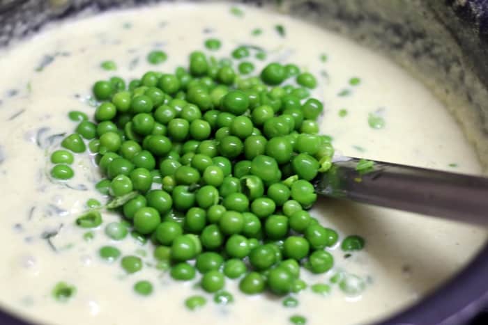 Blanched green peas added to methi matar malai gravy