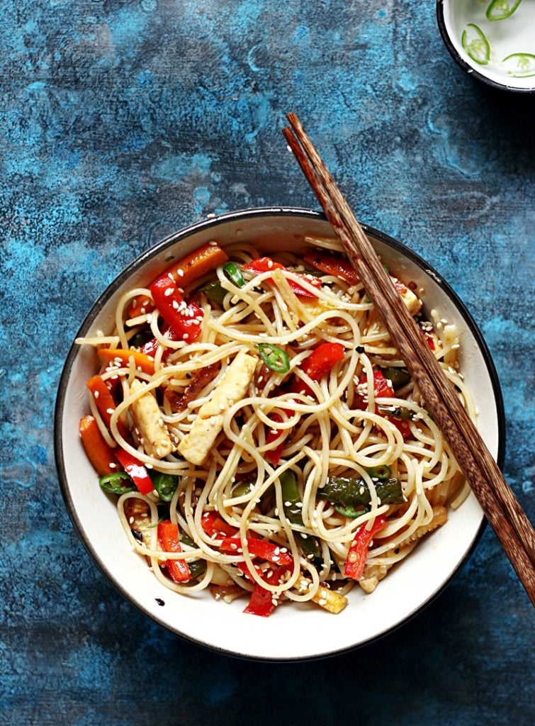 chilli garlic noodles served in a ceramic bowl with chopsticks