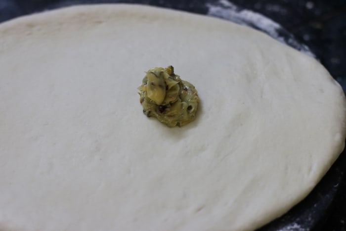 garlic butter placed on rolled dough for making herb garlic bread