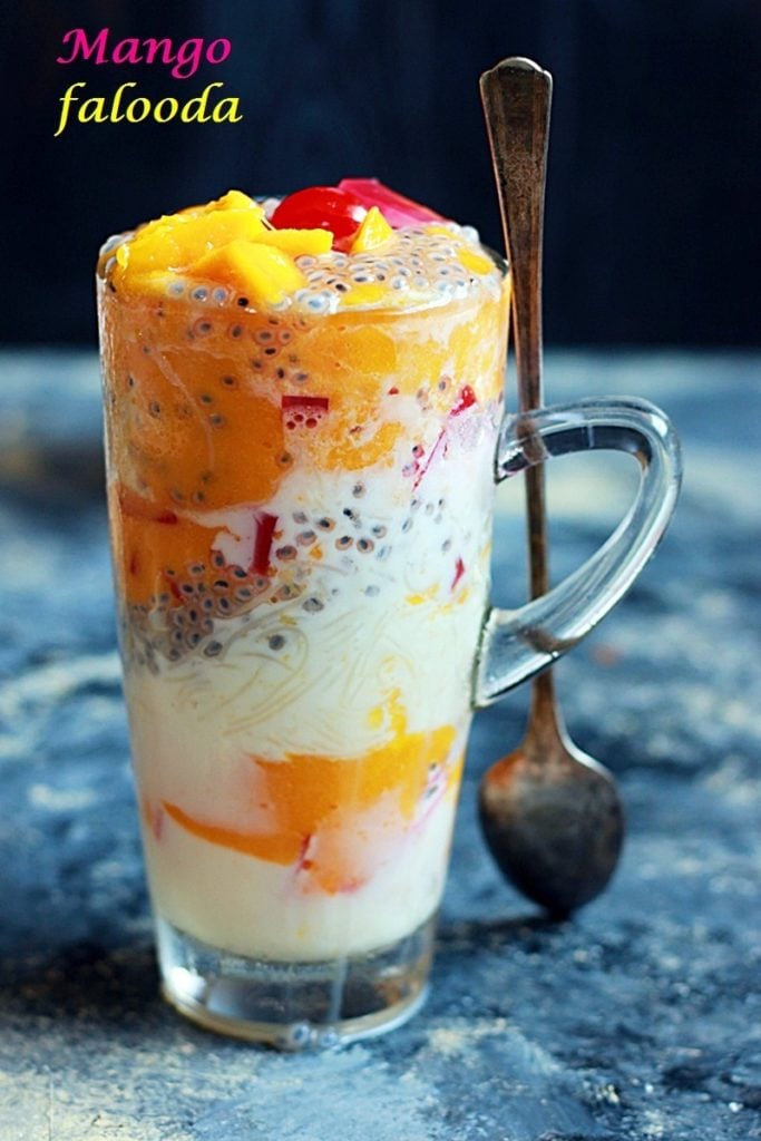 Refreshing mango falooda served in a tall glass with a spoon for dessert