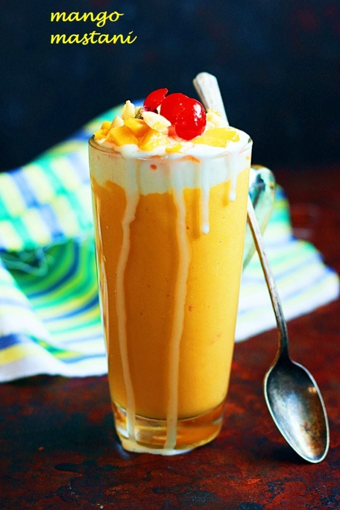 Delicious and thick pune special mango mastani in a tall glass with a spoon