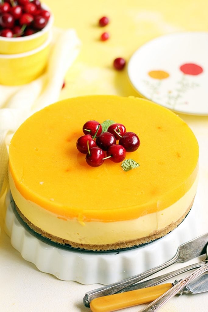 No bake mango cheesecake decorated with fresh cherries