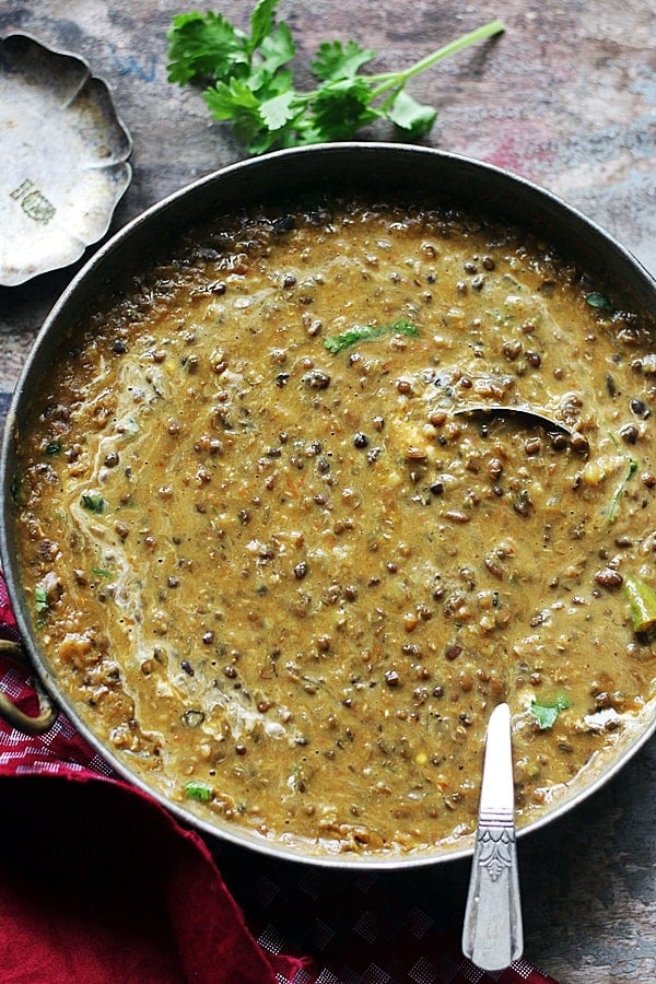 restaurant style dal makhani served in a copper pan with a spoon.