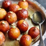 A silver plateful of homemade milk powder gulab jamuns garnished with pistachios