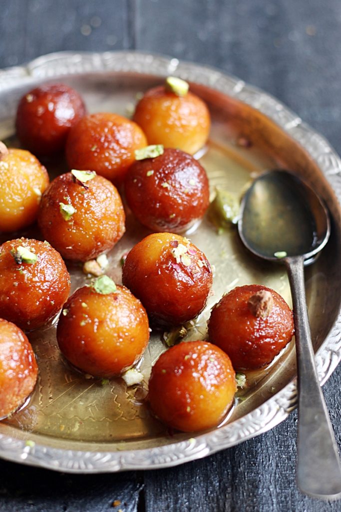 A silver plateful of homemade milk powder gulab jamuns garnished with pistachios