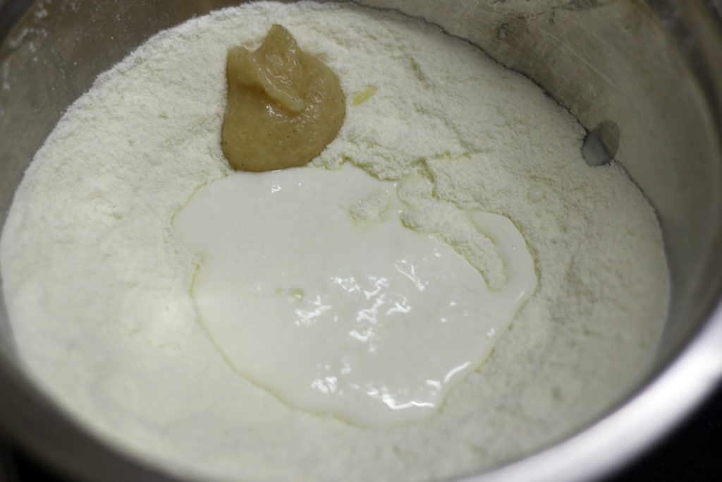 Milk powder, baking soda, ghee, curd and plain flour in a bowl for making gulab jamun.