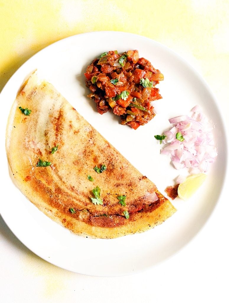 overhead shot of crispy paper thin pav bhaji dosa with side dish and chopped onions