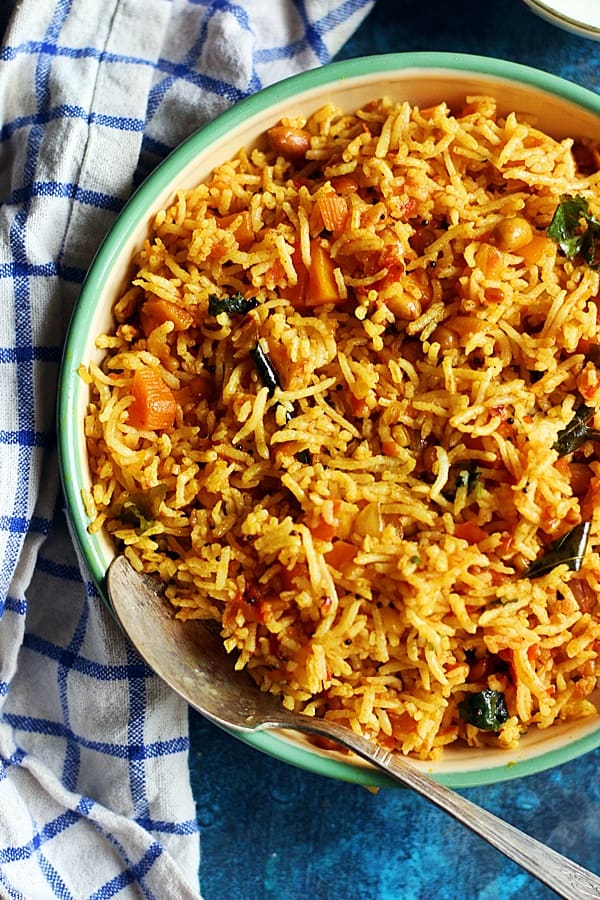 tomato rice served in  green enamel plate with a spoon