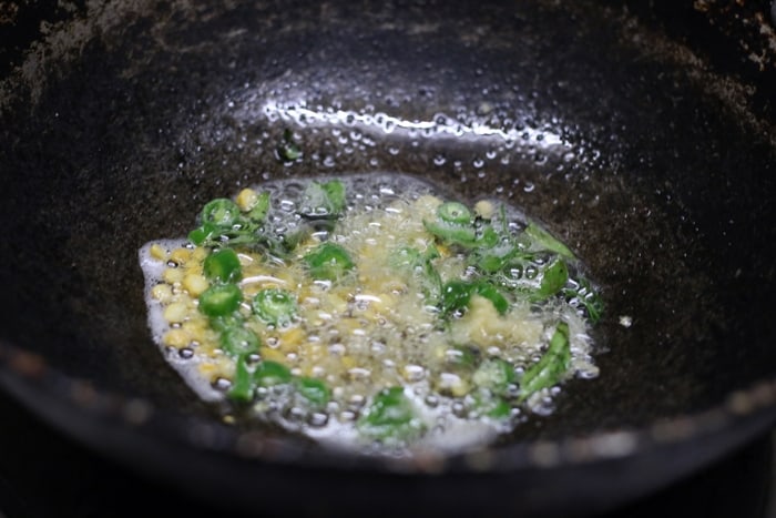 Tempering mustard seeds, urad dal, green chilies, curry leaves in oil