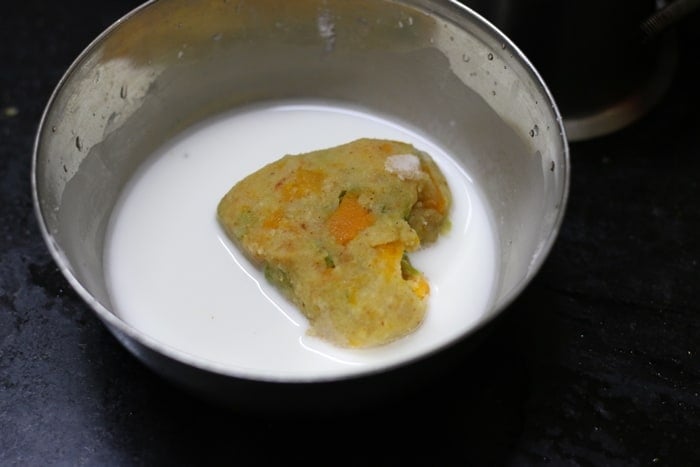 Dipping the shaped veg patty in corn flour slurry for making vegetable cutlet recipe.