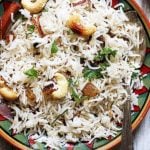 overhead shot of ghee rice garnished with fried cashews and raisins