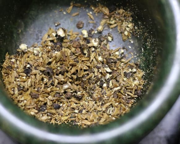 crushing peppercorns and cumin seeds in mortar and pestle