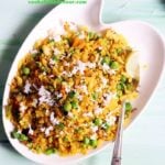 masala poha recipe- a white plate containing poha or rice flake with Indian spices