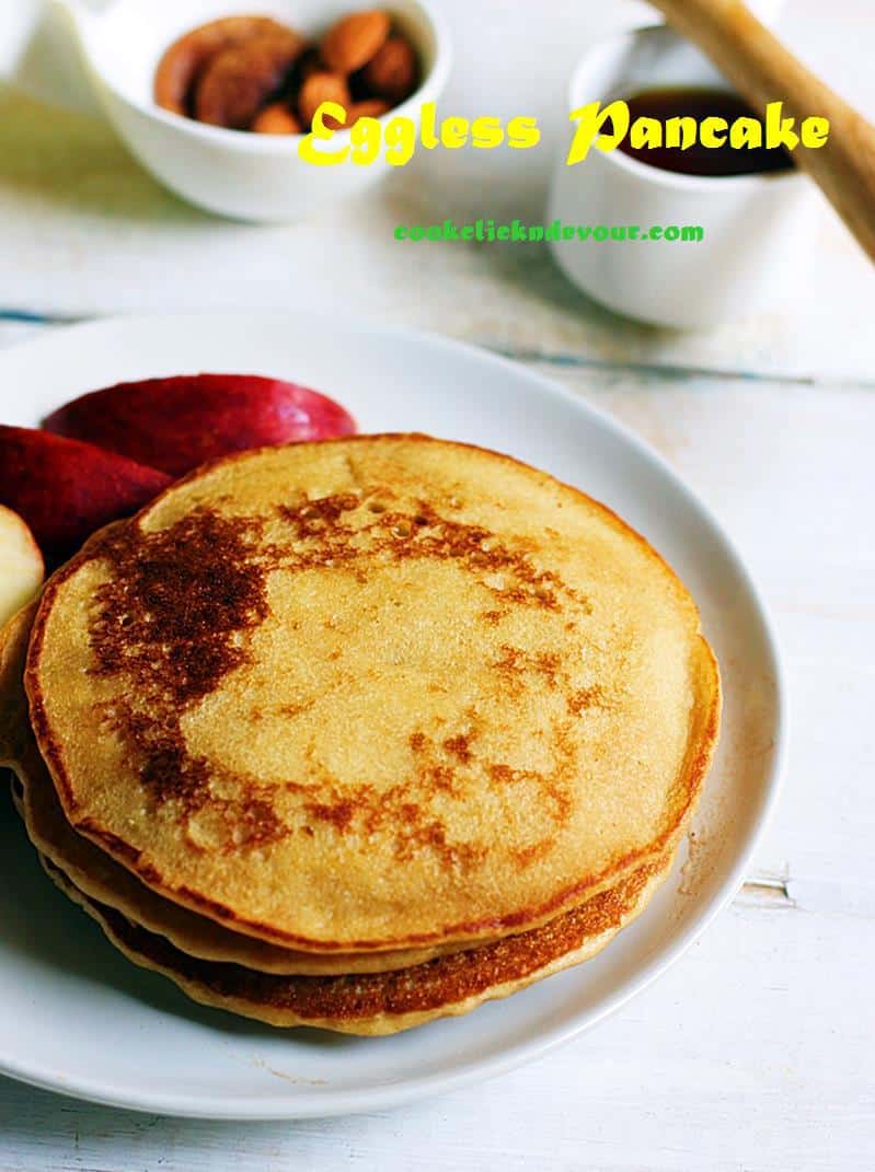 Fluffy, soft and tasty eggless pancakes served on a white plate for breakfast along with honey and fruits.