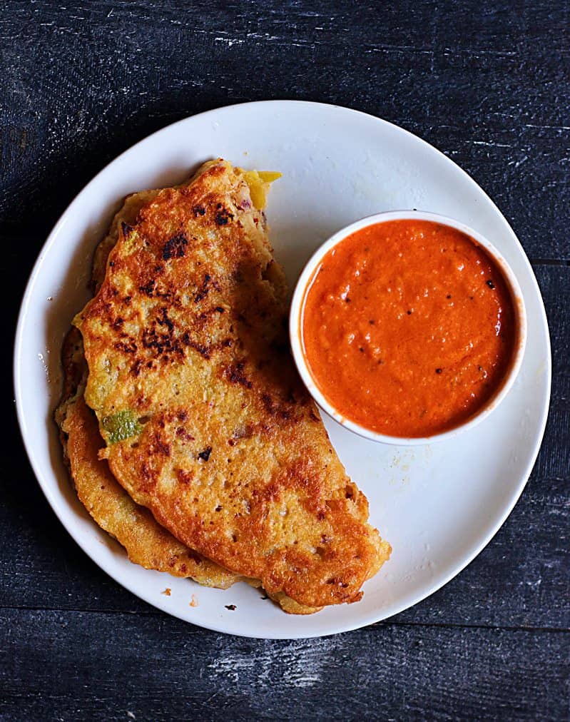 Adai served with tomato ginger chutney on a white plate