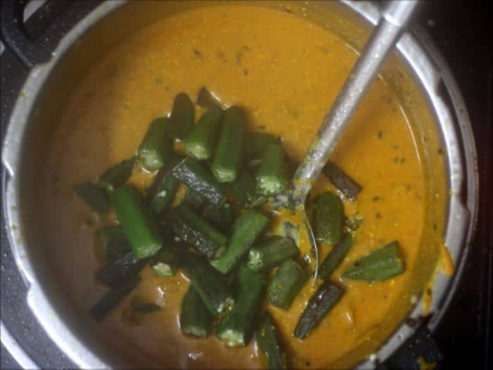 Adding sauteed okra for dahi bhindi recipe, dahi wali bhindi recipe