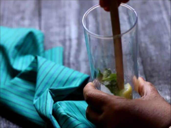 muddling ice cubes, mint leaves and sugar virgin pineapple mojito