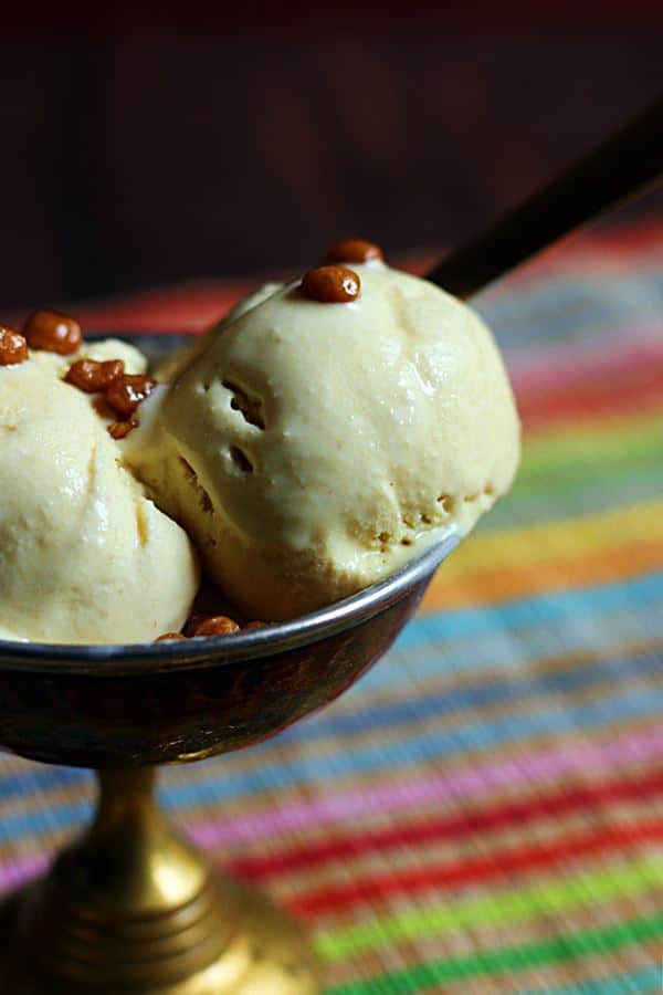 Two scoops of eggless no churn butterscotch ice cream in a copper ice cream bowl with a spoon