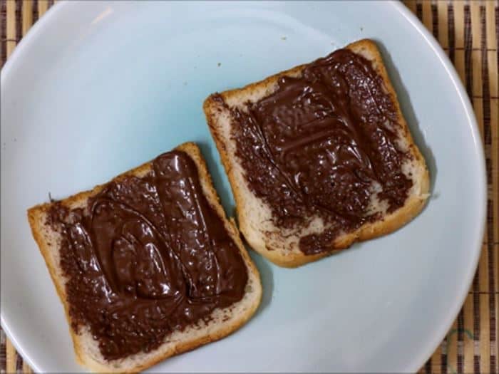 Spreading nutella on bread slices for chocolate sandwich