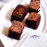 eggless chocolate cake recipe- wacky cake squares served on a white snack plate.